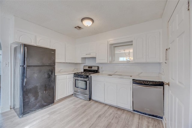 kitchen with dishwasher, white cabinets, gas stove, black fridge, and light hardwood / wood-style flooring