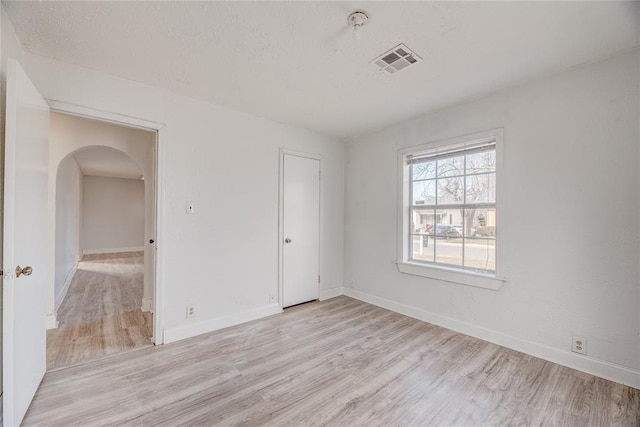 unfurnished room with light hardwood / wood-style flooring and a textured ceiling