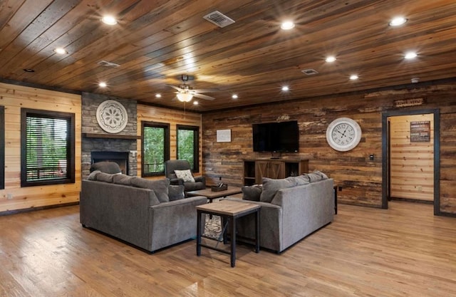 living room featuring light hardwood / wood-style flooring, ceiling fan, wooden walls, a fireplace, and wooden ceiling