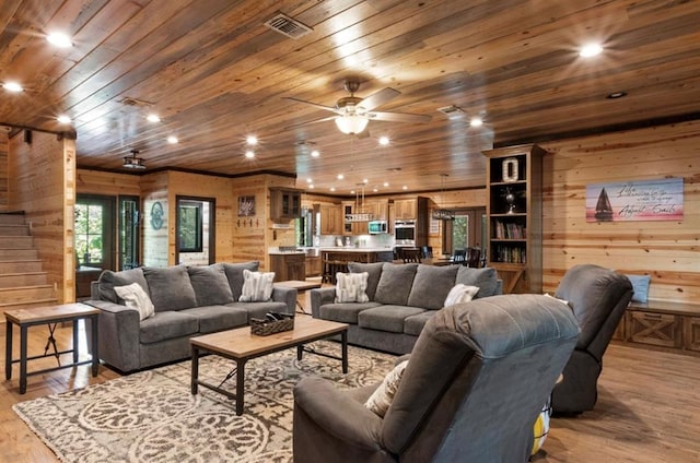 living room with wooden walls, wooden ceiling, light hardwood / wood-style floors, and ceiling fan