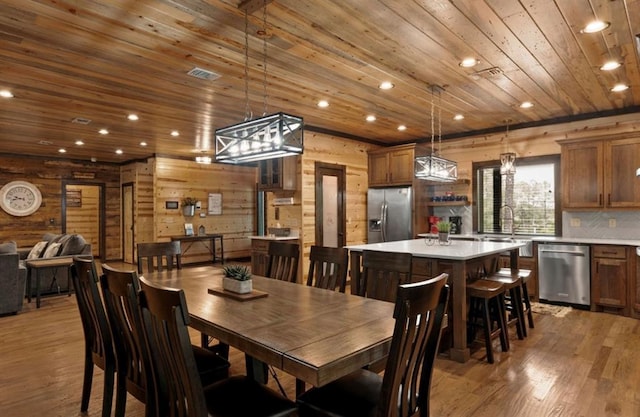 dining area with wood ceiling, wooden walls, and light hardwood / wood-style flooring