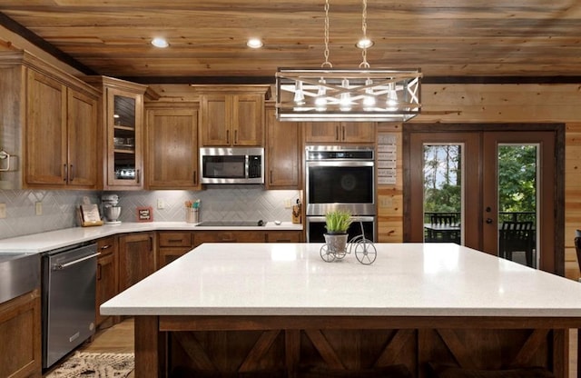 kitchen featuring stainless steel appliances, hanging light fixtures, a center island, and wooden ceiling