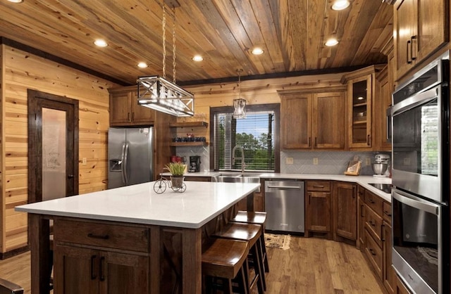 kitchen with tasteful backsplash, a center island, hanging light fixtures, wooden ceiling, and appliances with stainless steel finishes