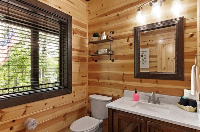 bathroom with vanity, toilet, and wood walls