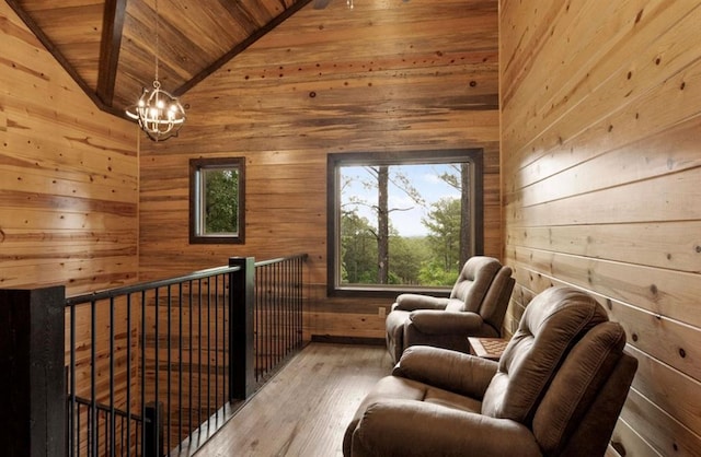 living area featuring wood walls, lofted ceiling, hardwood / wood-style flooring, wood ceiling, and an inviting chandelier