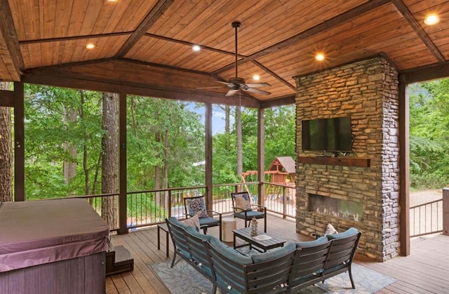 sunroom / solarium featuring ceiling fan, wood ceiling, vaulted ceiling, and an outdoor stone fireplace