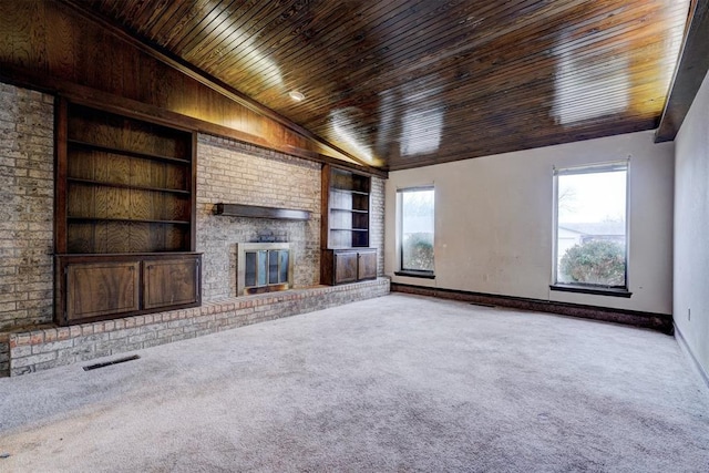 unfurnished living room with lofted ceiling, a healthy amount of sunlight, a fireplace, and built in shelves