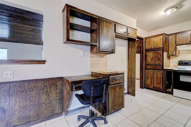 kitchen with tasteful backsplash, electric range oven, built in desk, and light tile patterned floors