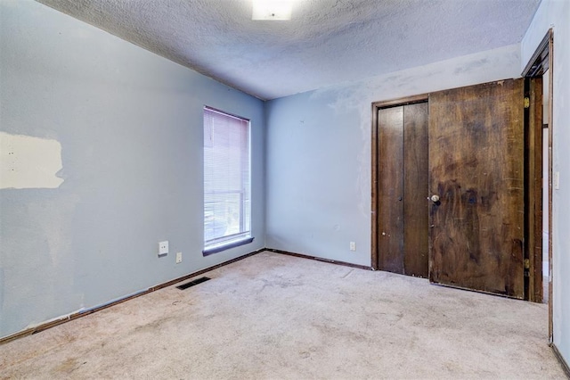 carpeted empty room featuring a textured ceiling