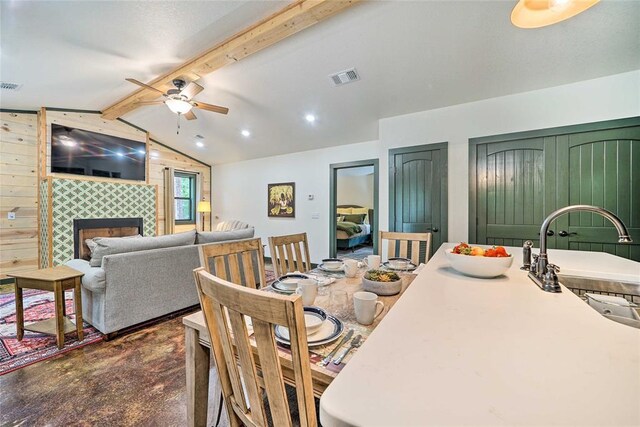 670 Pine Meadow Ln, Broken Bow, OK 74728 - dining room with sink, ceiling fan, vaulted ceiling with beams, a fireplace, and wood walls