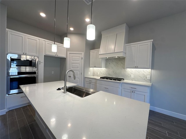 kitchen featuring pendant lighting, sink, appliances with stainless steel finishes, an island with sink, and white cabinets