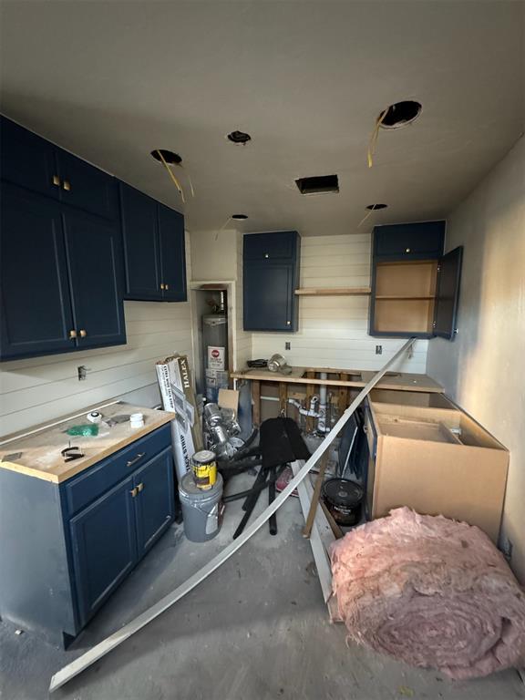 kitchen featuring blue cabinetry, concrete floors, and gas water heater