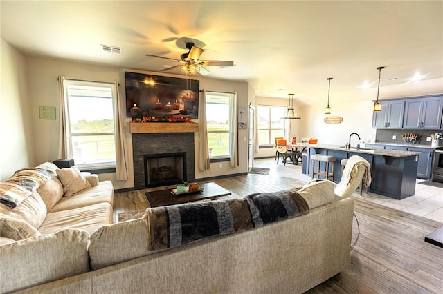 living room with sink, a wealth of natural light, a fireplace, and light hardwood / wood-style floors