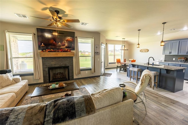 living room featuring ceiling fan, sink, and light hardwood / wood-style floors