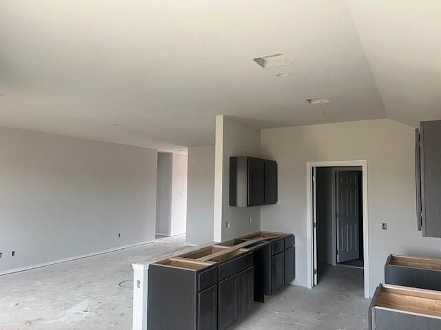 kitchen featuring dark cabinetry, concrete floors, and vaulted ceiling