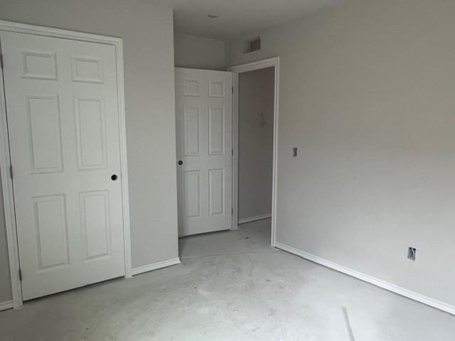 unfurnished bedroom with baseboards and unfinished concrete floors