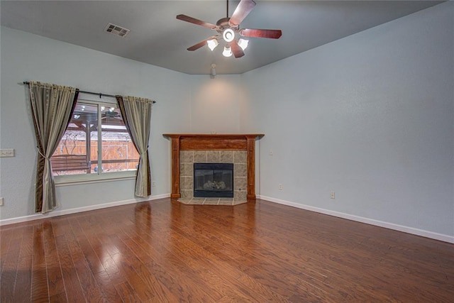 unfurnished living room featuring a tiled fireplace, hardwood / wood-style floors, and ceiling fan