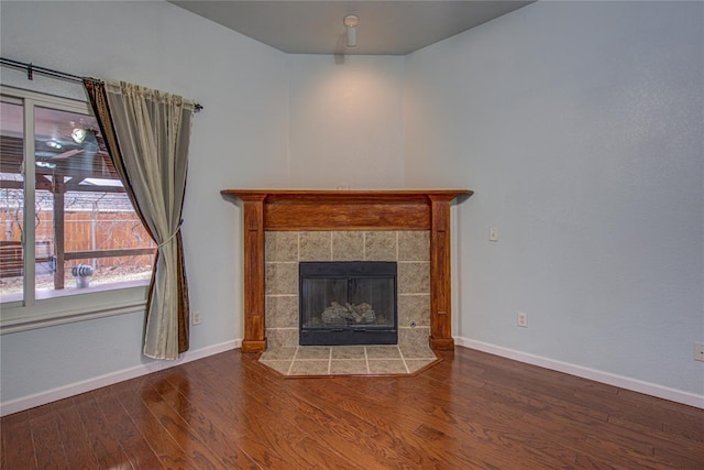 unfurnished living room featuring hardwood / wood-style flooring and a tiled fireplace