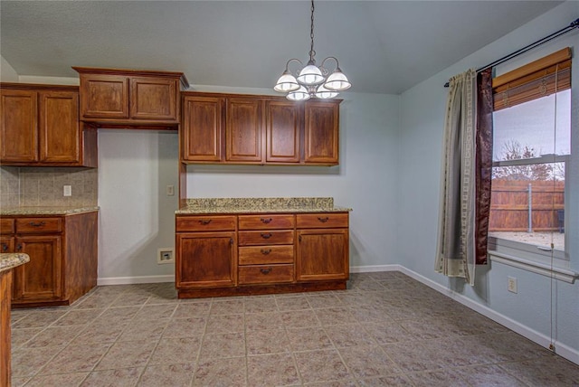 kitchen with pendant lighting, lofted ceiling, decorative backsplash, light stone counters, and an inviting chandelier