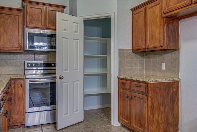 kitchen with decorative backsplash, light stone countertops, and oven