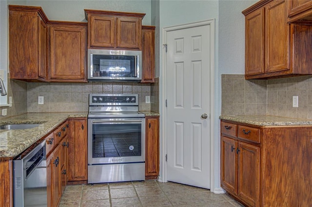 kitchen with tasteful backsplash, sink, light stone countertops, and appliances with stainless steel finishes