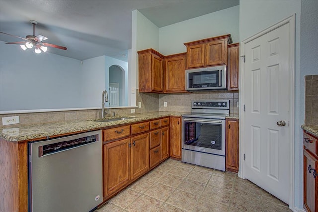 kitchen featuring light stone countertops, appliances with stainless steel finishes, sink, and decorative backsplash