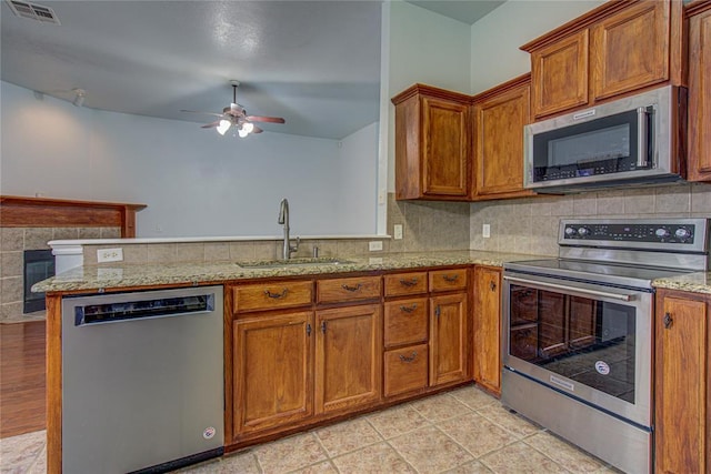 kitchen featuring sink, ceiling fan, appliances with stainless steel finishes, backsplash, and kitchen peninsula