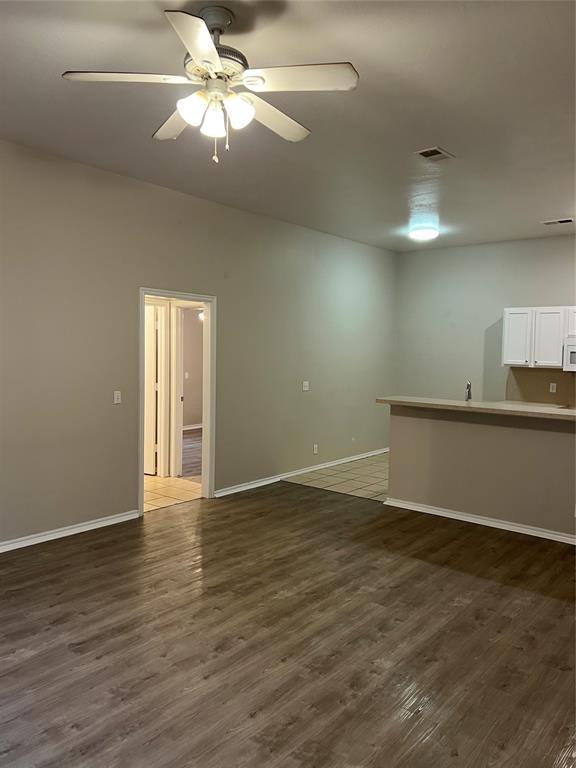 unfurnished living room with dark hardwood / wood-style floors and ceiling fan