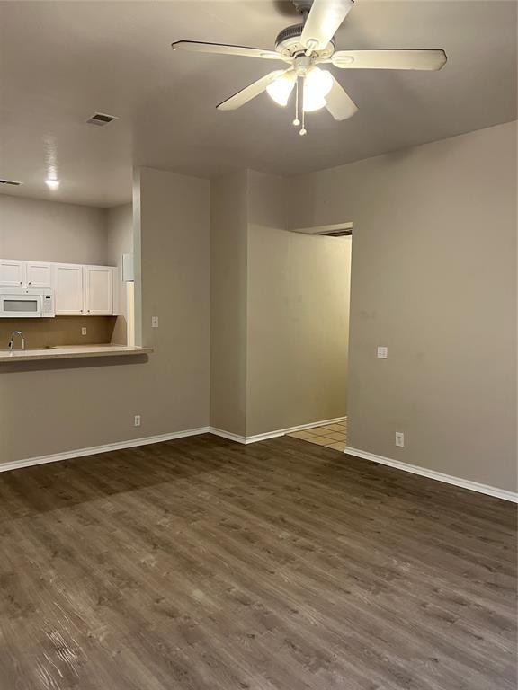 unfurnished living room with dark hardwood / wood-style floors and ceiling fan