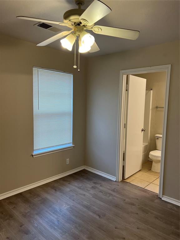 unfurnished bedroom with connected bathroom, hardwood / wood-style floors, and ceiling fan