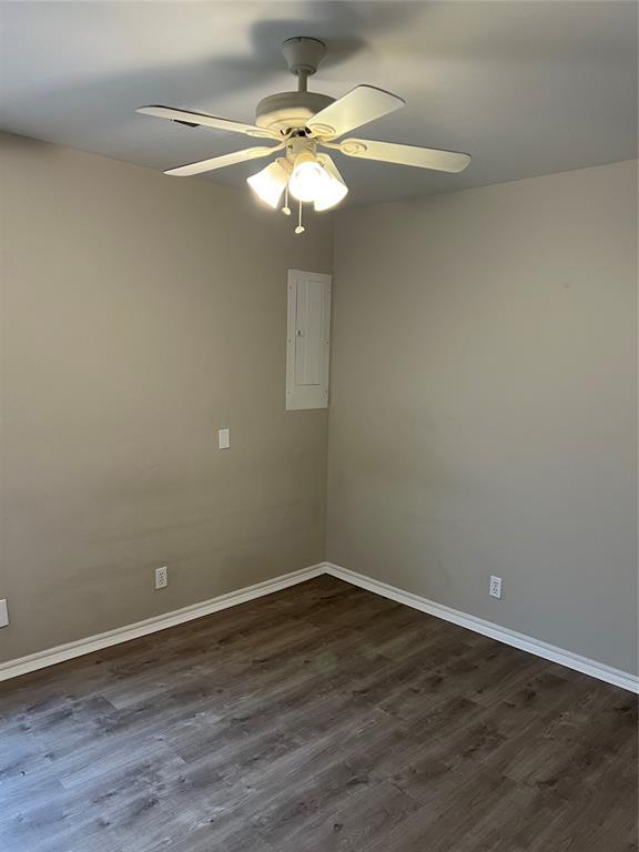 spare room featuring dark wood-type flooring, electric panel, and ceiling fan