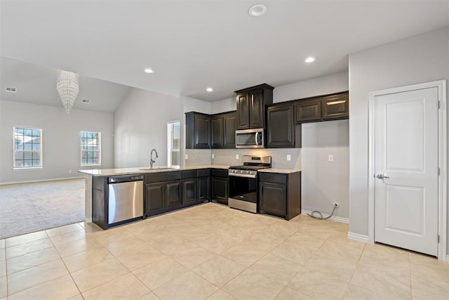 kitchen featuring light tile patterned flooring, dark brown cabinetry, sink, appliances with stainless steel finishes, and light stone countertops