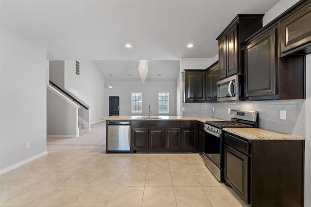 kitchen with sink, appliances with stainless steel finishes, tasteful backsplash, light tile patterned flooring, and kitchen peninsula