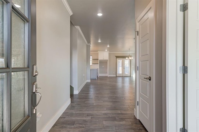 foyer with crown molding, dark hardwood / wood-style floors, and a notable chandelier