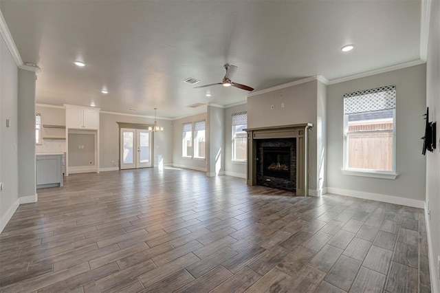 unfurnished living room with crown molding and ceiling fan with notable chandelier