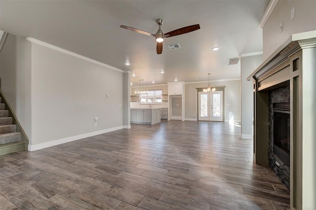 unfurnished living room with crown molding, ceiling fan with notable chandelier, dark hardwood / wood-style floors, and french doors