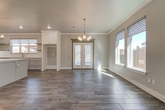 kitchen with french doors, sink, an inviting chandelier, decorative light fixtures, and white cabinets