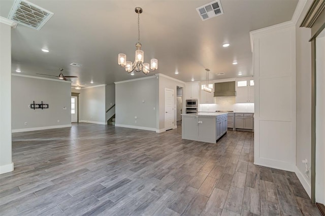 kitchen with hardwood / wood-style flooring, hanging light fixtures, a center island, ornamental molding, and ceiling fan with notable chandelier