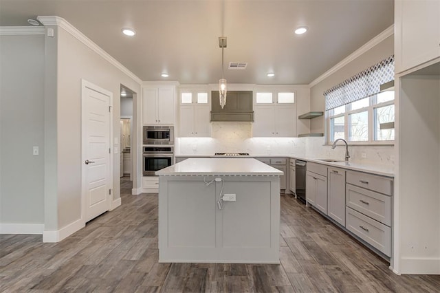 kitchen featuring decorative light fixtures, sink, decorative backsplash, a center island, and crown molding