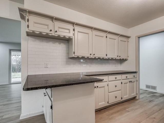 kitchen featuring tasteful backsplash, a textured ceiling, and light wood-type flooring