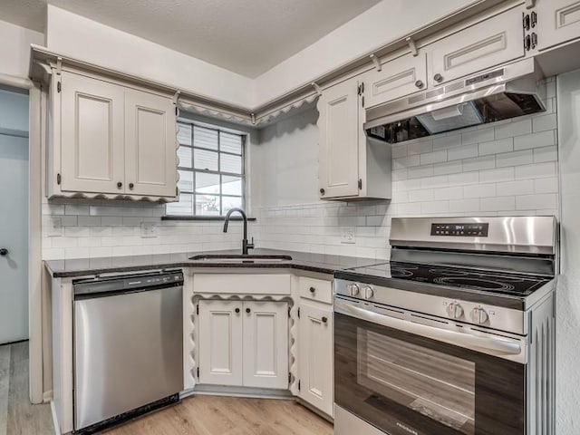 kitchen with sink, tasteful backsplash, light wood-type flooring, stainless steel appliances, and white cabinets