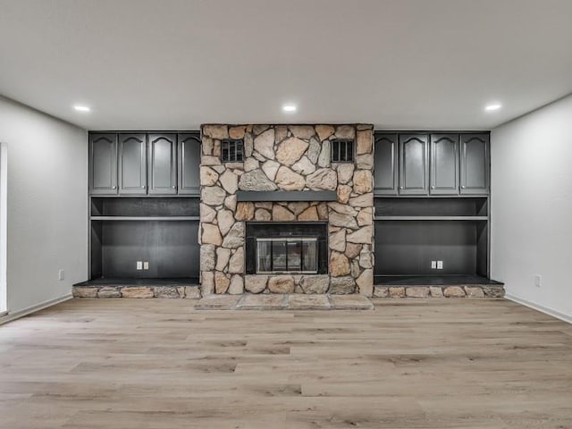 unfurnished living room with a stone fireplace and light hardwood / wood-style floors