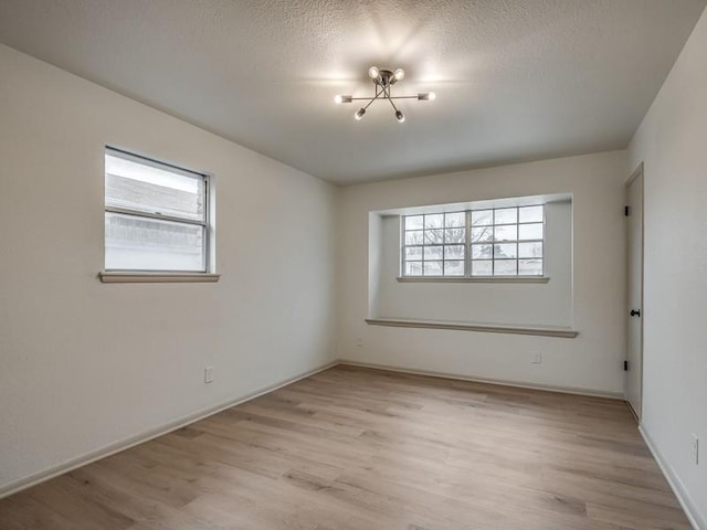 empty room with a textured ceiling, light hardwood / wood-style floors, and a healthy amount of sunlight