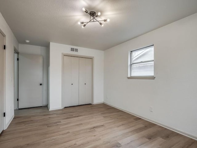 unfurnished bedroom featuring a closet, a textured ceiling, and light hardwood / wood-style flooring