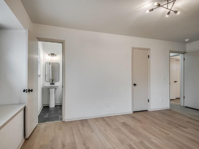 unfurnished bedroom featuring ensuite bath and light hardwood / wood-style flooring