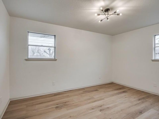 empty room with a textured ceiling and light hardwood / wood-style flooring