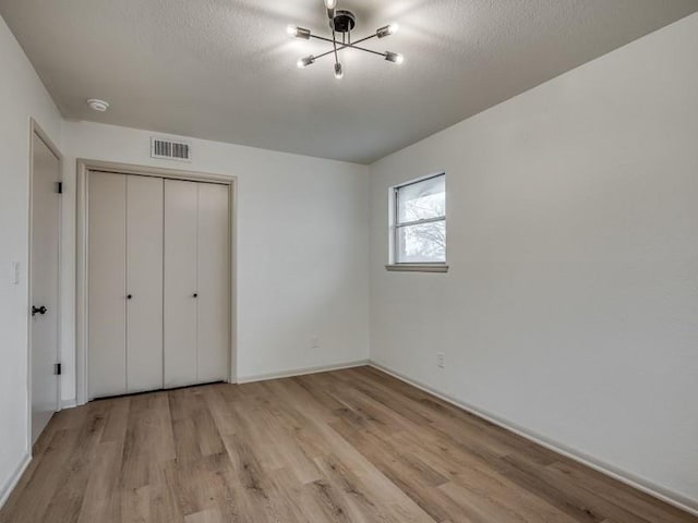 unfurnished bedroom featuring a textured ceiling, a closet, and light wood-type flooring