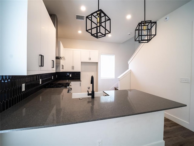 kitchen featuring white cabinetry, dark stone counters, kitchen peninsula, and hanging light fixtures