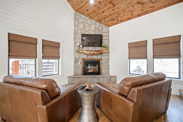living room featuring lofted ceiling, wood finished floors, a fireplace, wood ceiling, and wooden walls