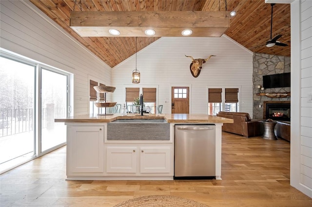 kitchen featuring wood ceiling, dishwasher, a sink, open floor plan, and a stone fireplace